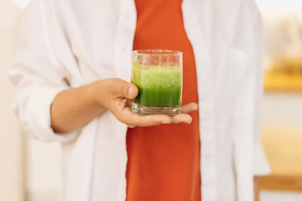 Verre de smoothie vert tenu à la main